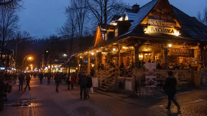 A highland inn with a lit-up veranda in the evening